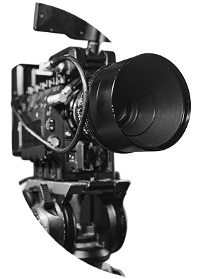 Close-up of a professional camera with a large lens on a tripod, shown in black and white. The image has a dramatic and focused tone.