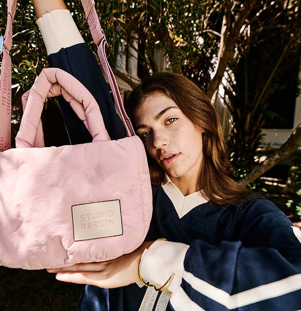 Woman outdoors holding a pink bag labeled 